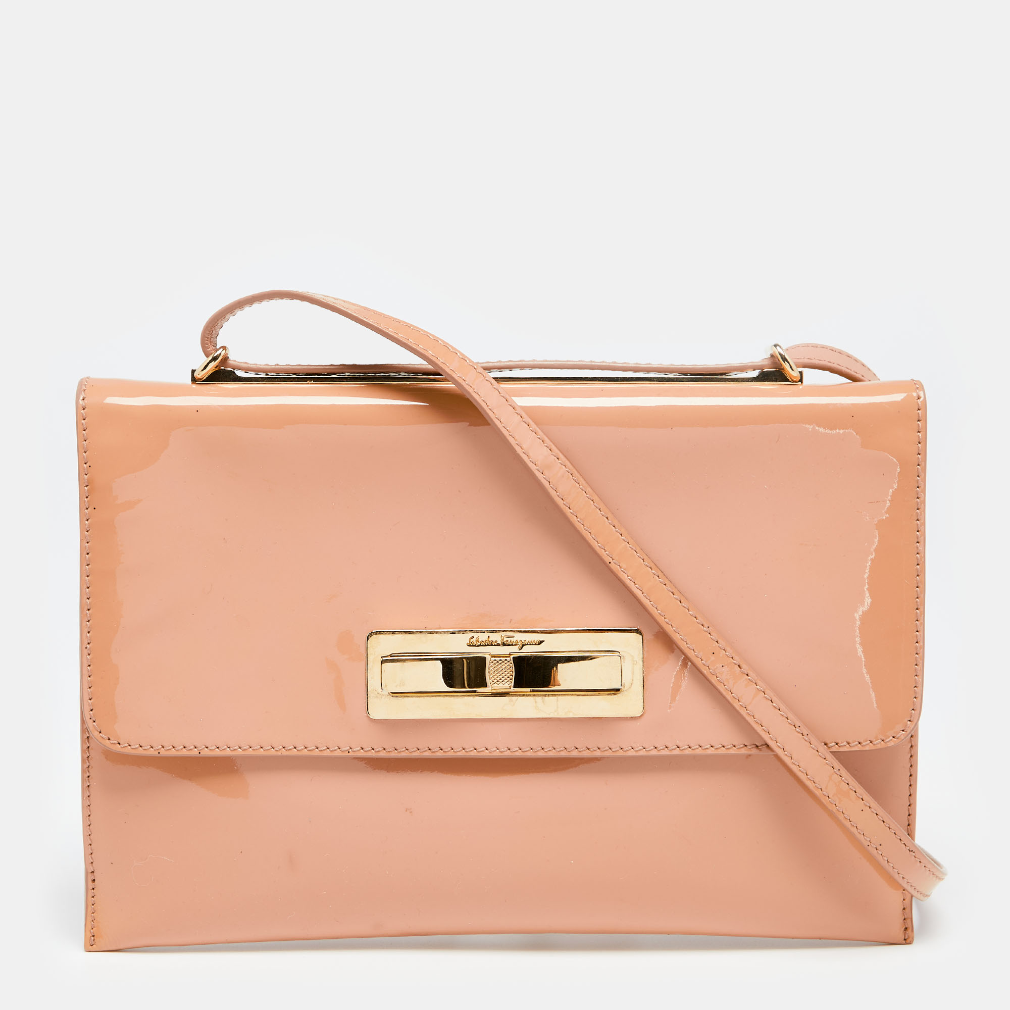 This designer shoulder bag from Salvatore Ferragamo is crafted from peach patent leather. The bag features a bow detailed flap closure a shoulder strap and a leather lined interior. This creation is easy to carry on any day.
