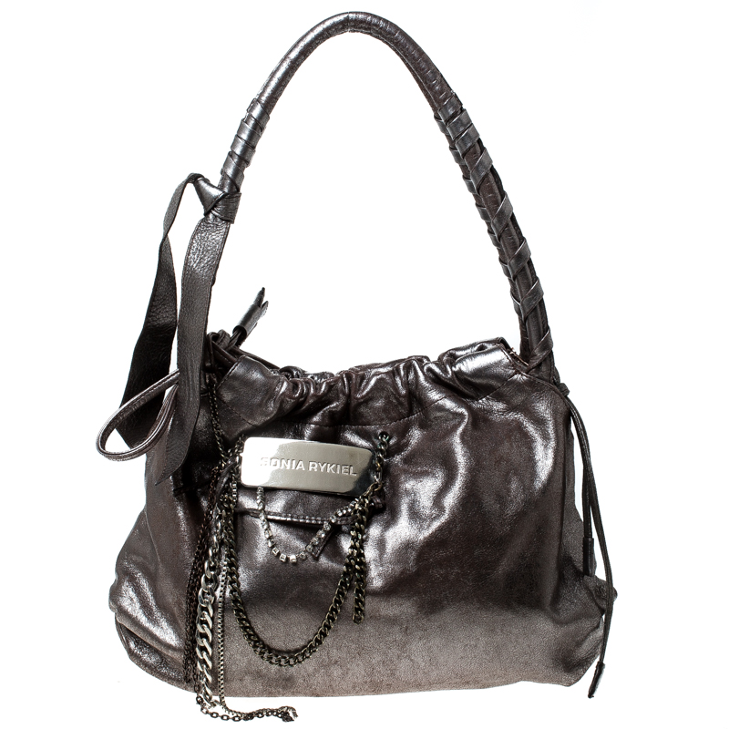 Flaunt your fashion quotient by adorning this top class handbag from Sonia Rykiel. This leather bag is brilliantly fashioned in keeping with trends. Lined with fabric the interior of this bag is spacious. The silver bag features dual handles and chain detailing on the front.