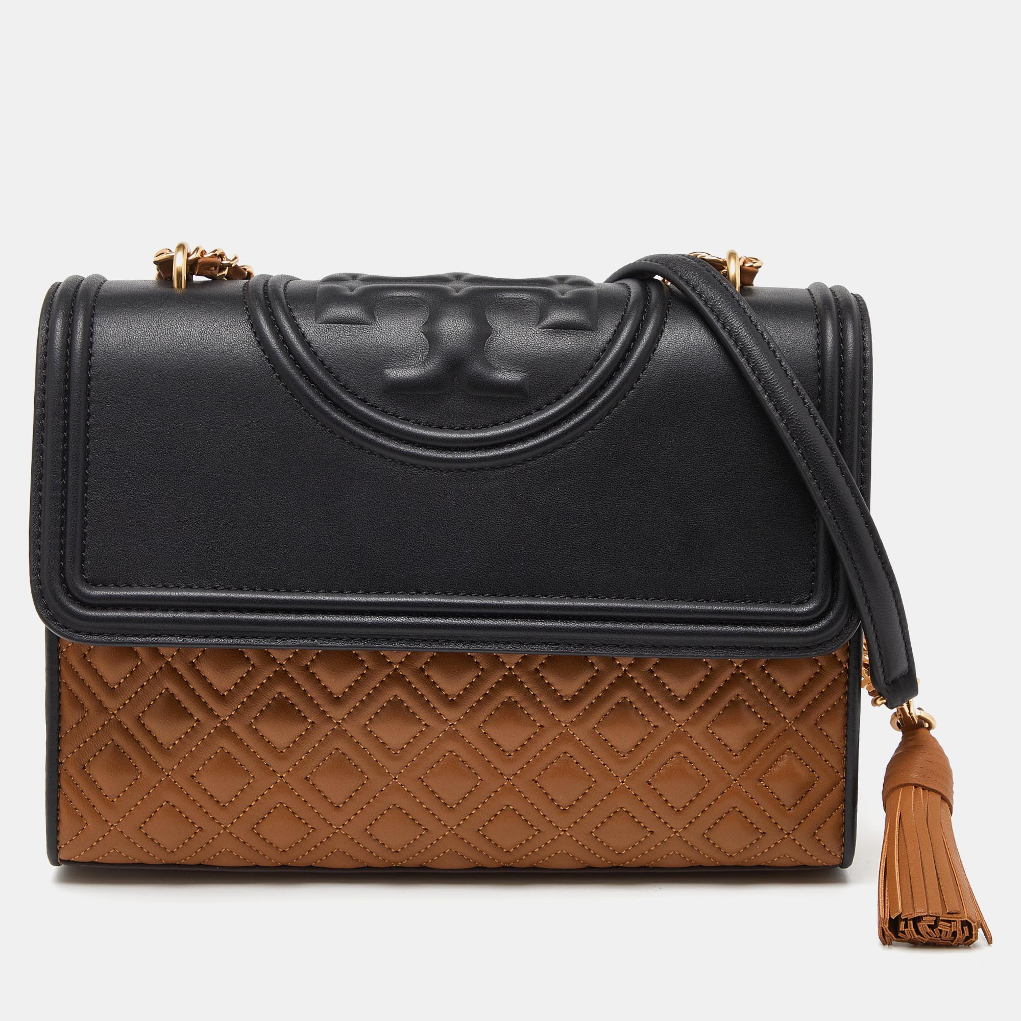 This Fleming shoulder bag from Tory Burch has been meticulously crafted from leather and designed with quilts in diamond patterns and the logo on the top. The flap opens to a fabric lined interior and the bag is held by an interwoven chain link.