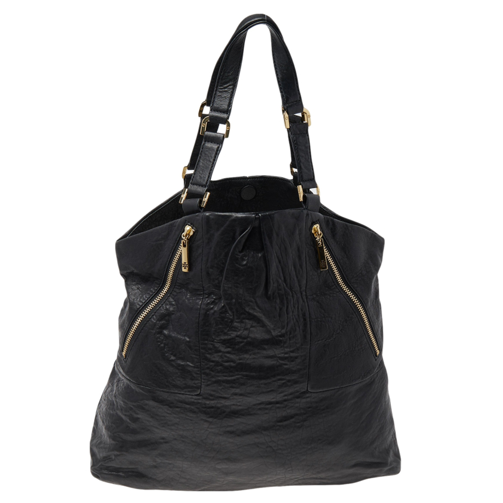 Featuring dual handles and a classic black shade this Tory Burch tote exudes just the right amount of sophistication. The leather bag comes equipped with a capacious canvas compartment to house all your daily essentials. Flaunting logo detailed zips at the front this piece is definitely an ideal buy