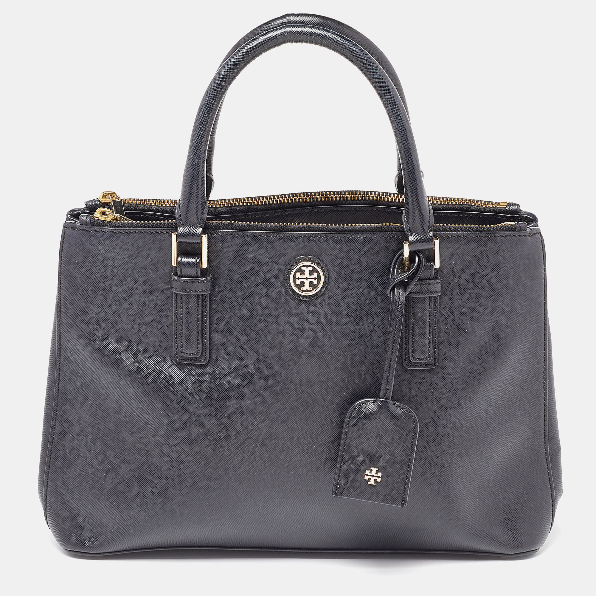 This stunning black tote is by Tory Burch. Crafted from leather and lined with fabric on the insides the bag features a lovely exterior adorned with floral laser cut design all over. It has dual rolled top handles logo on the front and two zipper pockets on the top.