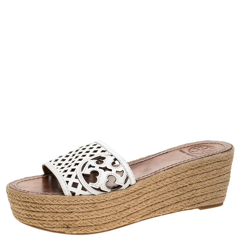 Complete your outfit with these Tory Burch wedge sandals. They are made from white leather and feature open toes espadrille wedge heels and the brand logo cutouts on the vamps. The insoles are leather lined.