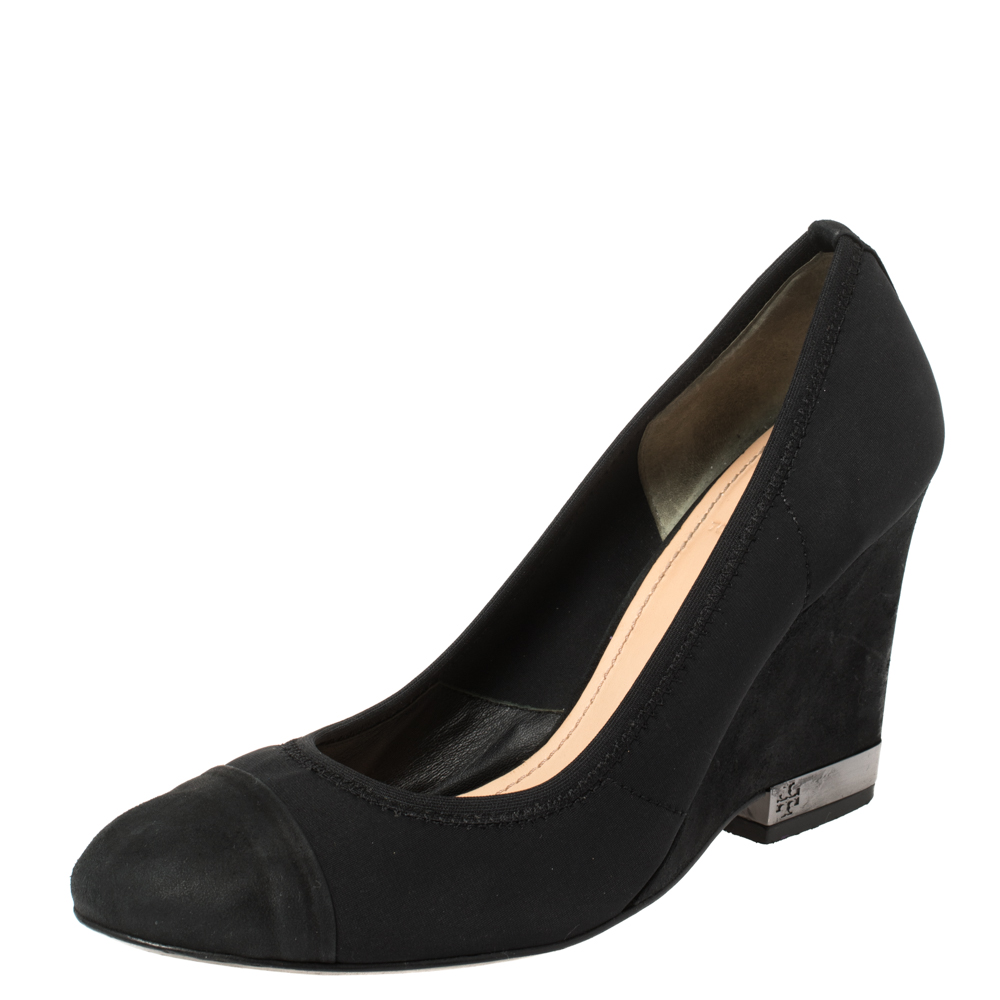 These black Tory Burch pumps are simply elegant and luxe. Crafted from quality suede they flaunt tonal cap toes 9 cm wedge heels and durable soles. This pair is just what you need to heighten your style quotient.