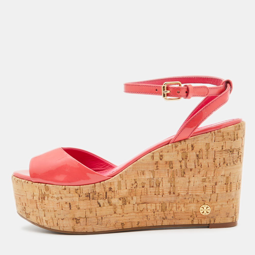 Its easy to fall in love with these sandals by Tory Burch. Created from pink patent leather they are defined by an ankle buckle closure cork incorporated wedge heels with a brand signature at the side and rubber soles.